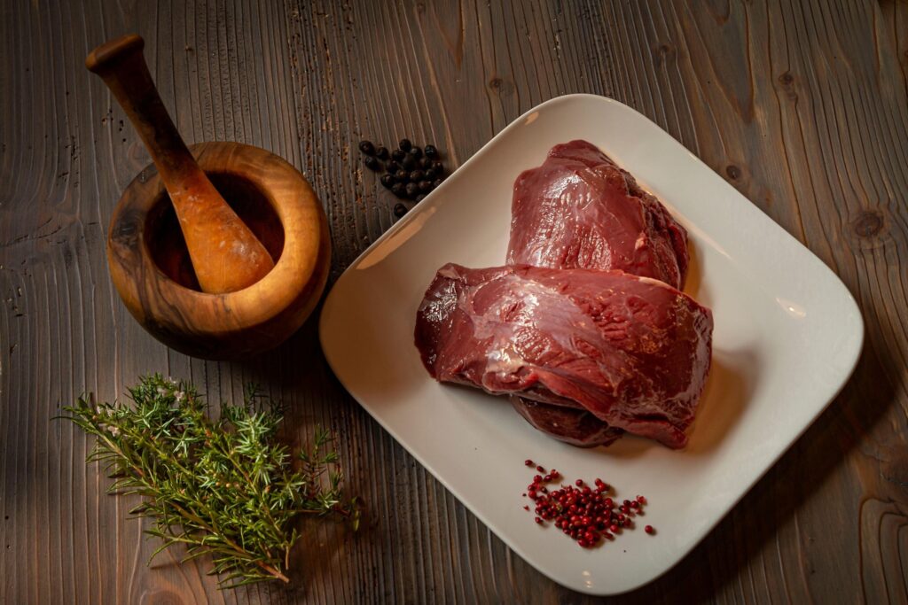 Venison on a plate, mortar and pestle next to it